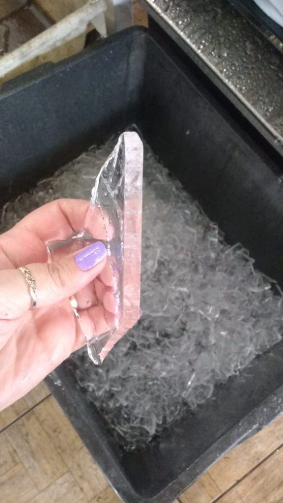 A imagem mostra a mão de uma pessoa segurando um gelo em escamas.  