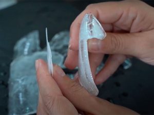 A imagem mostra as mãos de uma pessoa segurando um gelo em flocos e um gelo em escamas.